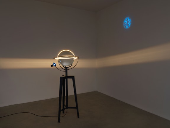 Olafur Eliasson, <em>Model for decelerated light</em>, 2021. Steel tripod, glass sphere, coloured glass sphere (blue), brass ring, aluminium, paint (black), LED light, ballast, 65 3/4 x 29 1/2 x 23 5/8 inches. Courtesy the artist and Tanya Bonakdar Gallery, New York / Los Angeles.