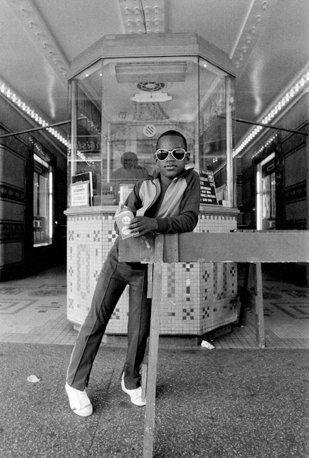 Dawoud Bey, <em>A Boy in Front of the Loew's 125th Street Movie Theater, Harlem, NY from Harlem, U.S.A.</em>, 1976. Gelatin silver print (printed 2019), 14 x 11 inches. Collection of the artist; courtesy Sean Kelly Gallery, New York; Stephen Daiter Gallery, Chicago; and Rena Bransten Gallery, San Francisco. © Dawoud Bey.