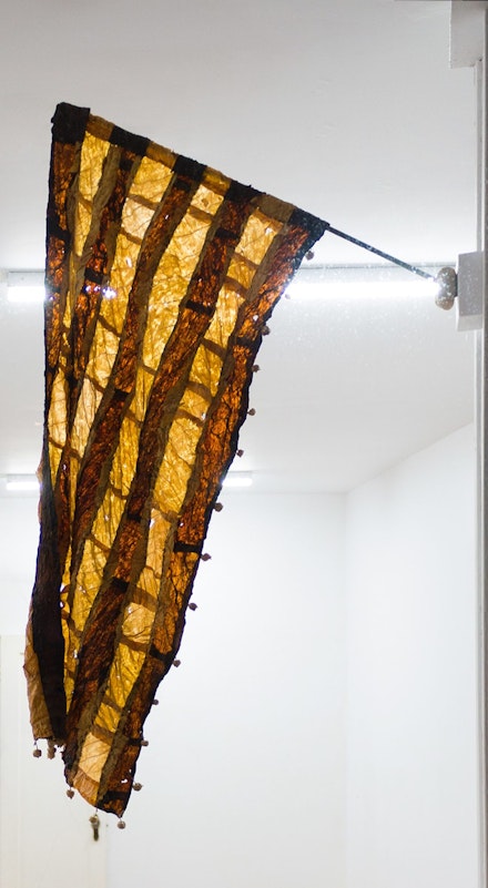 Gabrielle L’Hirondelle Hill, <em>Dispersal</em>, 2019. Virginia tobacco, Perique tobacco, thread, seed pods, support stocking, and found pole, 43 x 14 5/16 inches. Courtesy the artist and Unit 17, Vancouver, and Cooper Cole, Toronto © Gabrielle L’Hirondelle Hill.