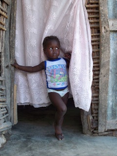 A Haitian boy stands in a hut with new concrete flooring, laid by missionary workers. Photo by Kaitlin Failing. 